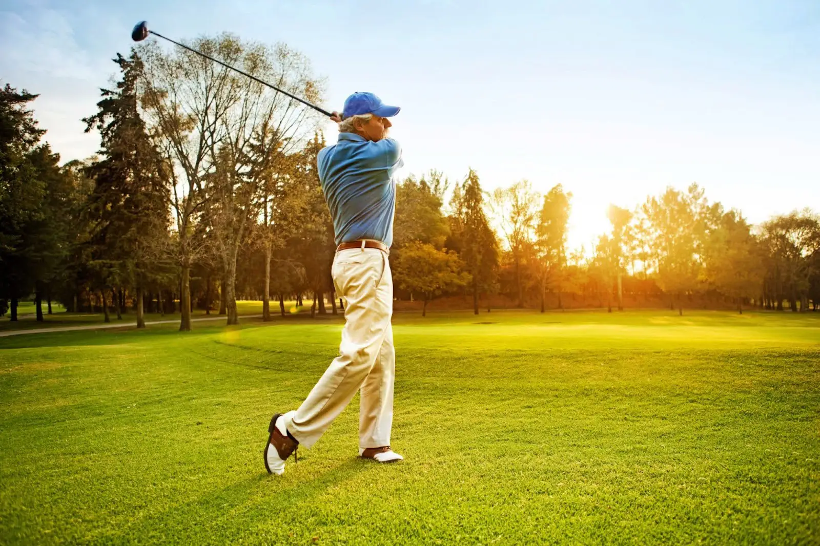 Senior golfer teeing off at sunset