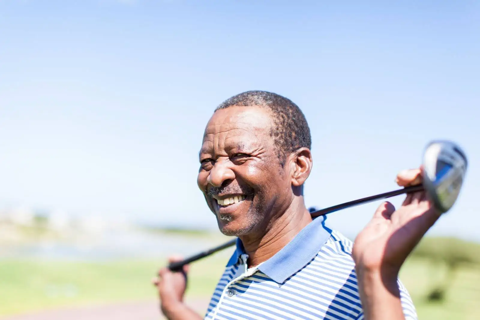 Senior golfer smiling with his driver over his shoulders