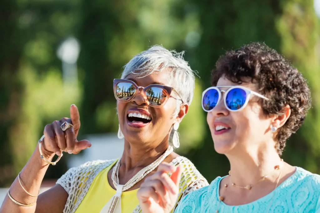 Two senior women wearing sunglasses and laughing